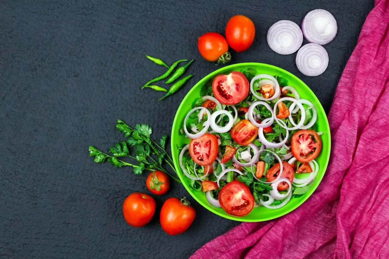 A vibrant vegetable salad featuring tomatoes, onions, and greens in a colorful setting.